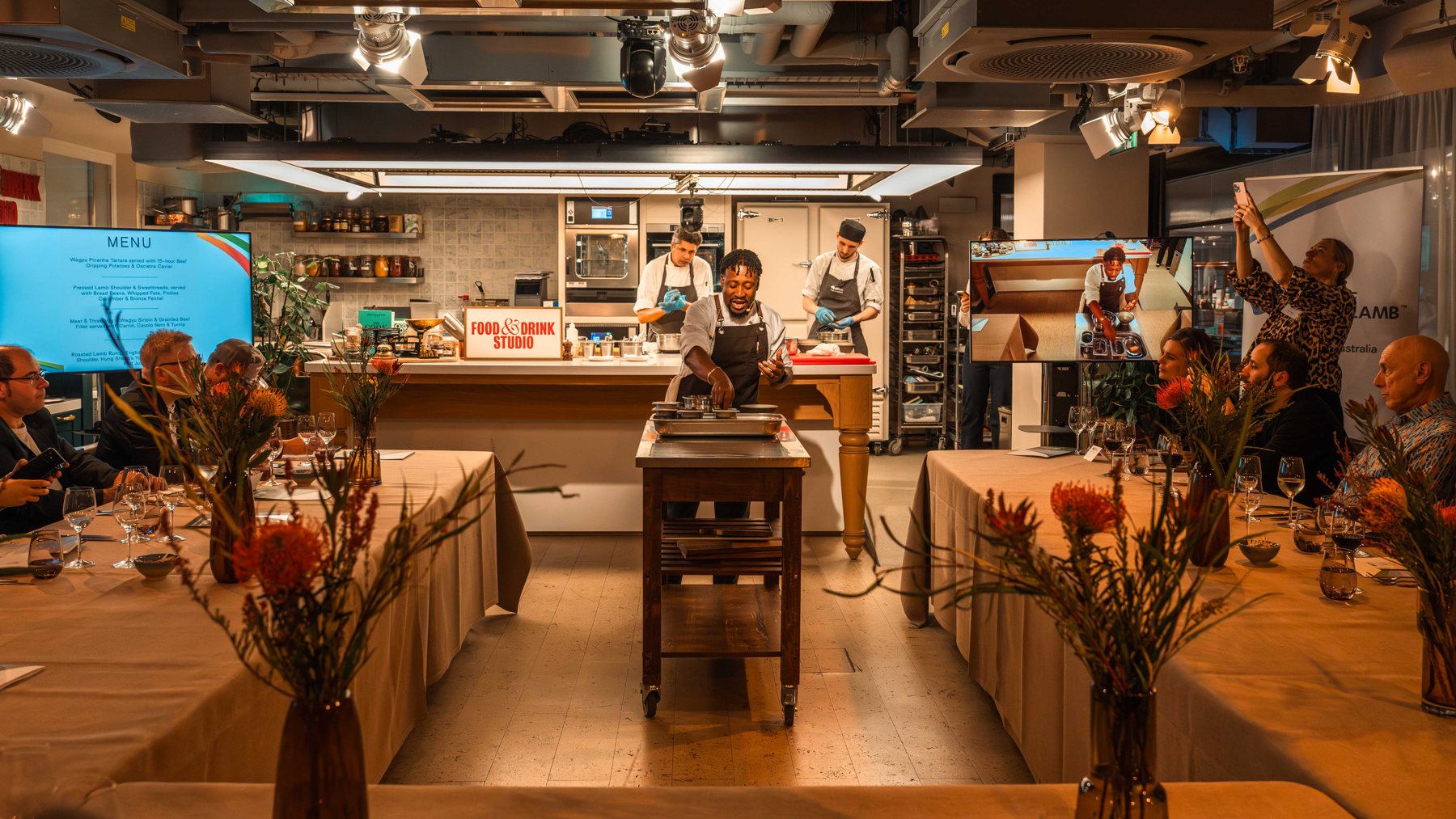Guests and chefs in a restaurant kitchen and dining space