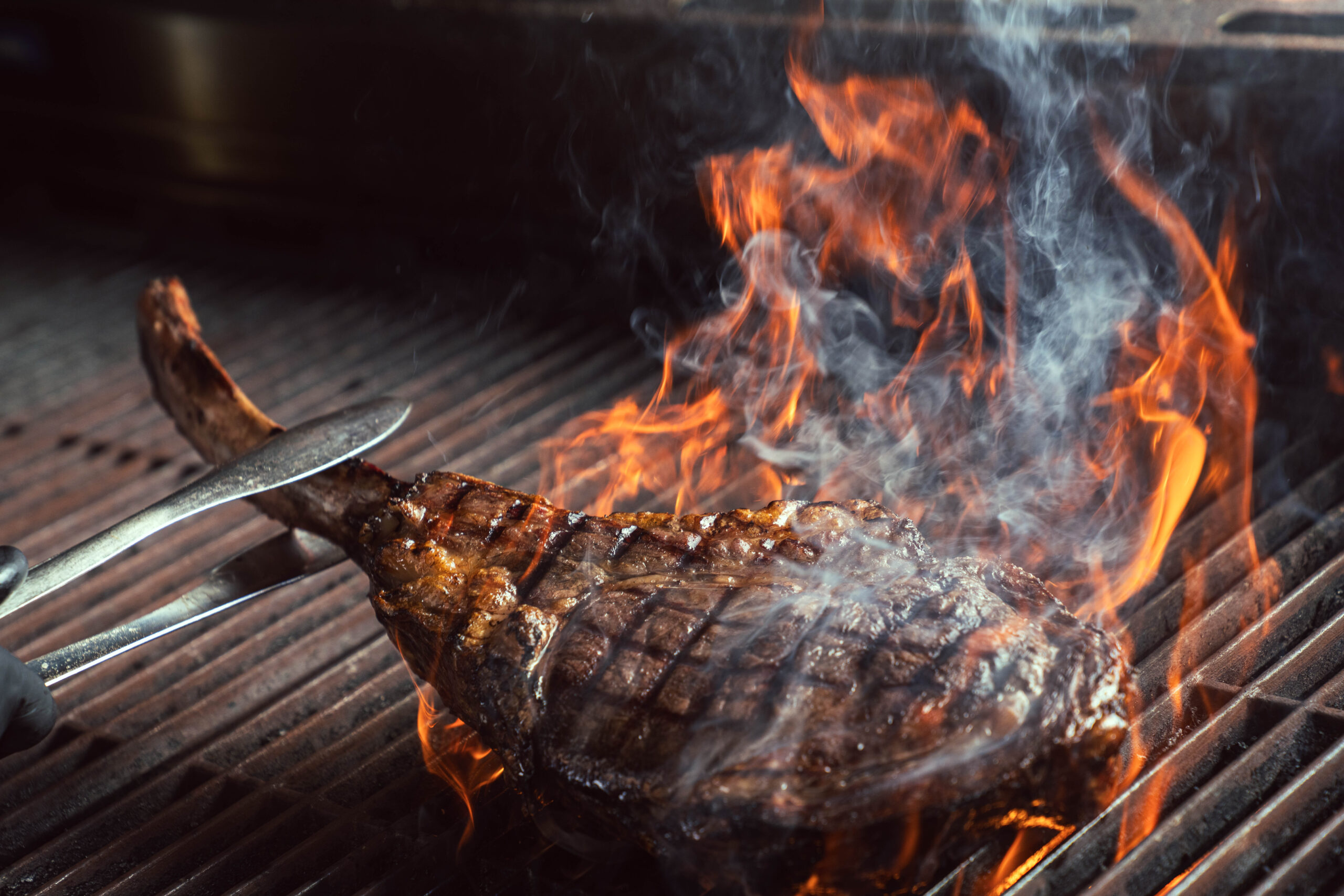 Steak cooking over flames on a grill